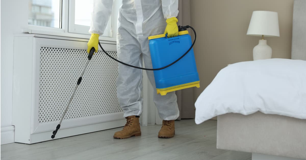 Pest control technician spraying the floor of a rental home in Boise